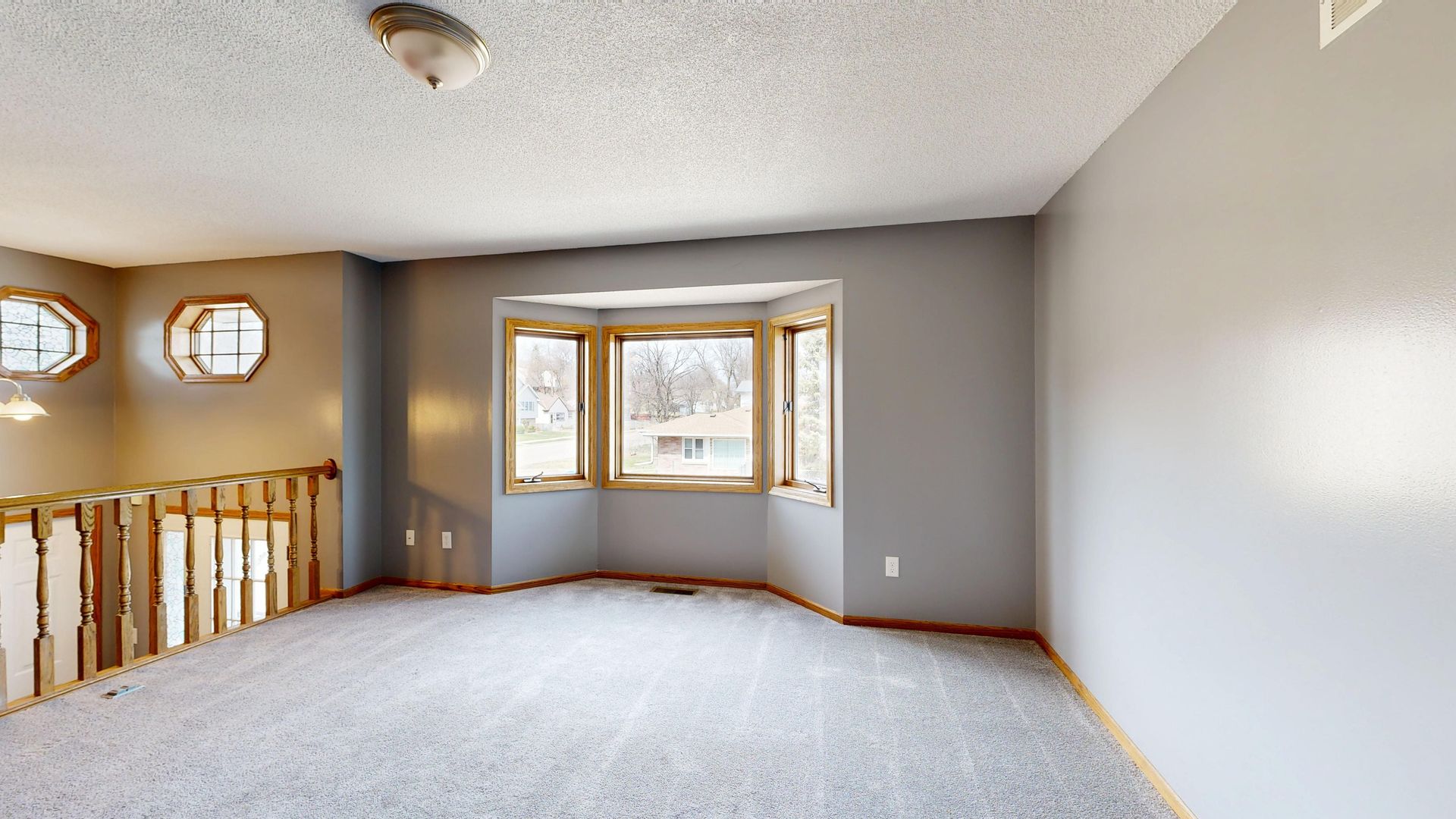 Empty room with large bay window and wooden accents, ideal for real estate.